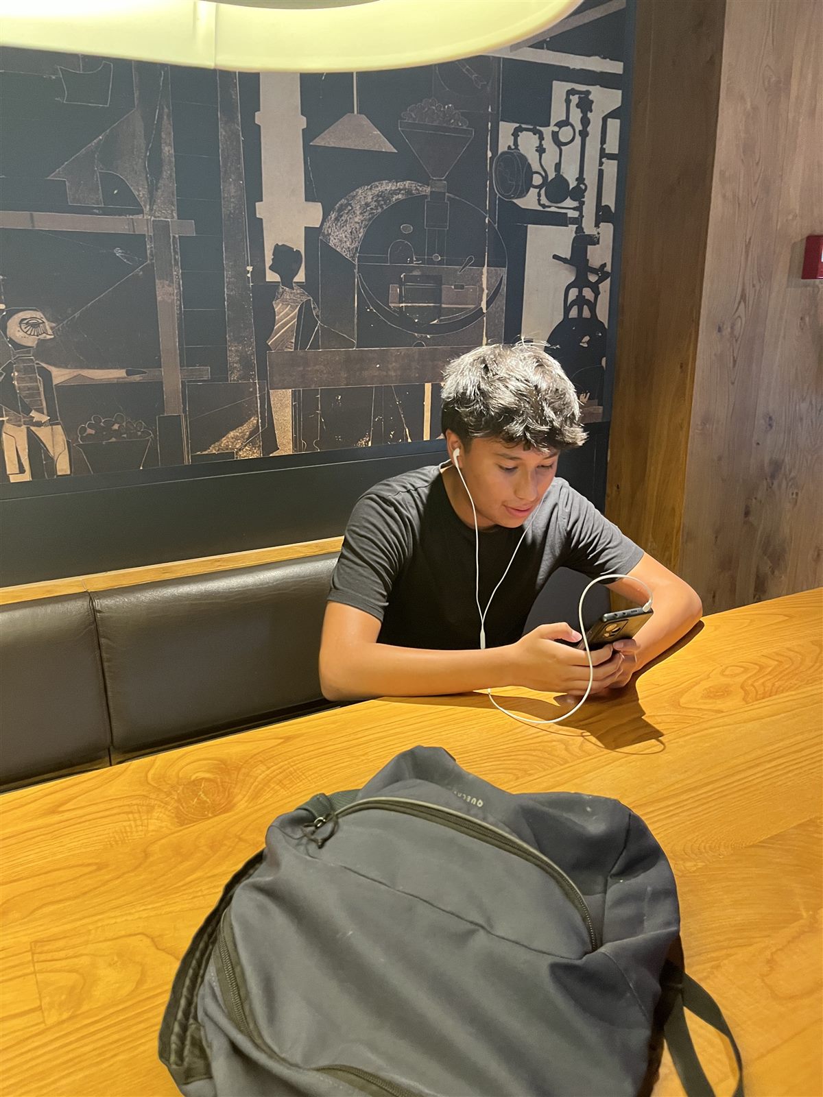 Charles Coronel sentado a una mesa, con auriculares, mirando el móvil